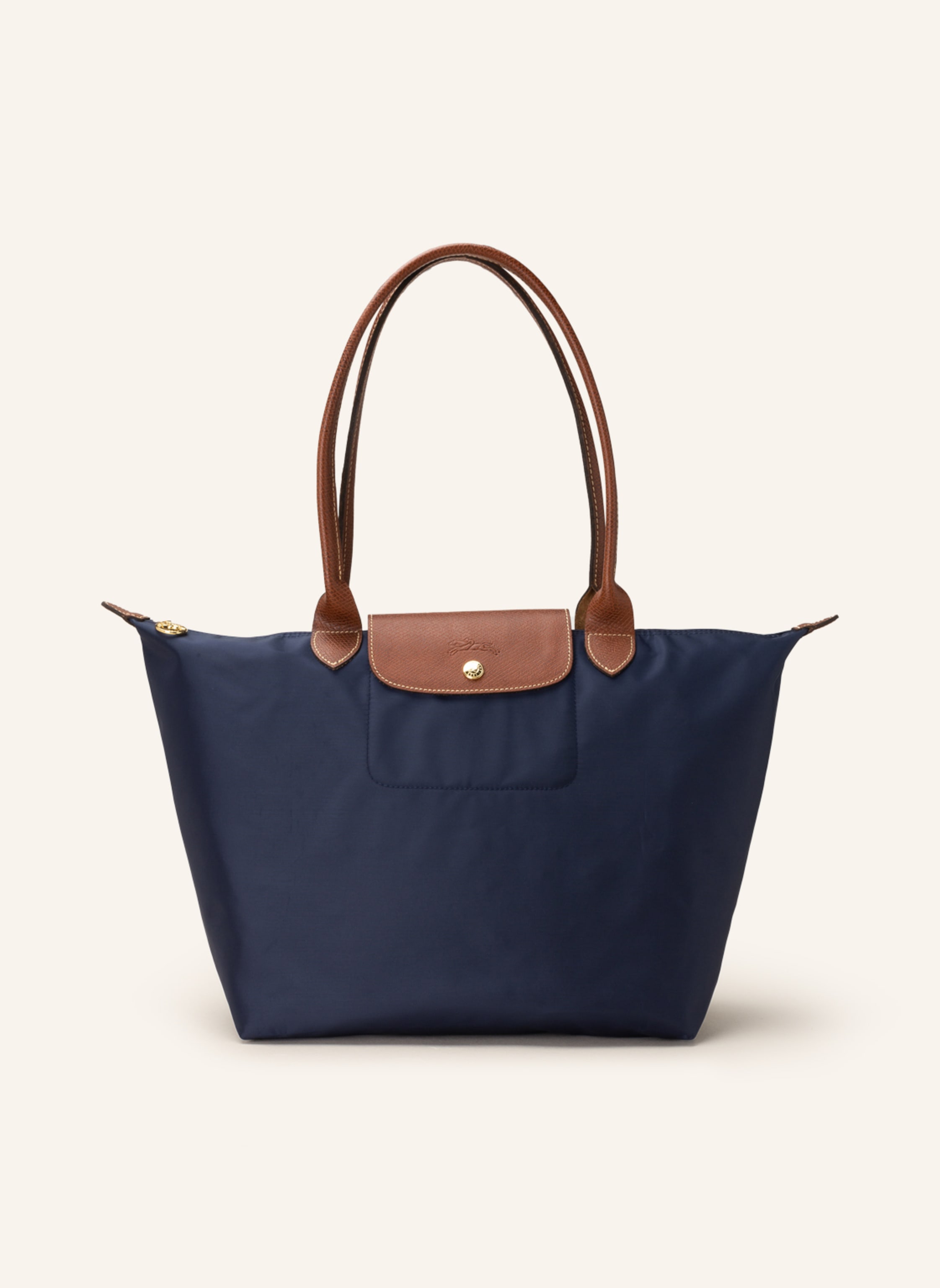 Longchamp Nylon und Leder. Tragehenkel. Schließt mit Reißverschluss. Lederbesatz mit Druckknopf und Logo-Prägung. Faltbar. Innentasche in dunkelblau / braun