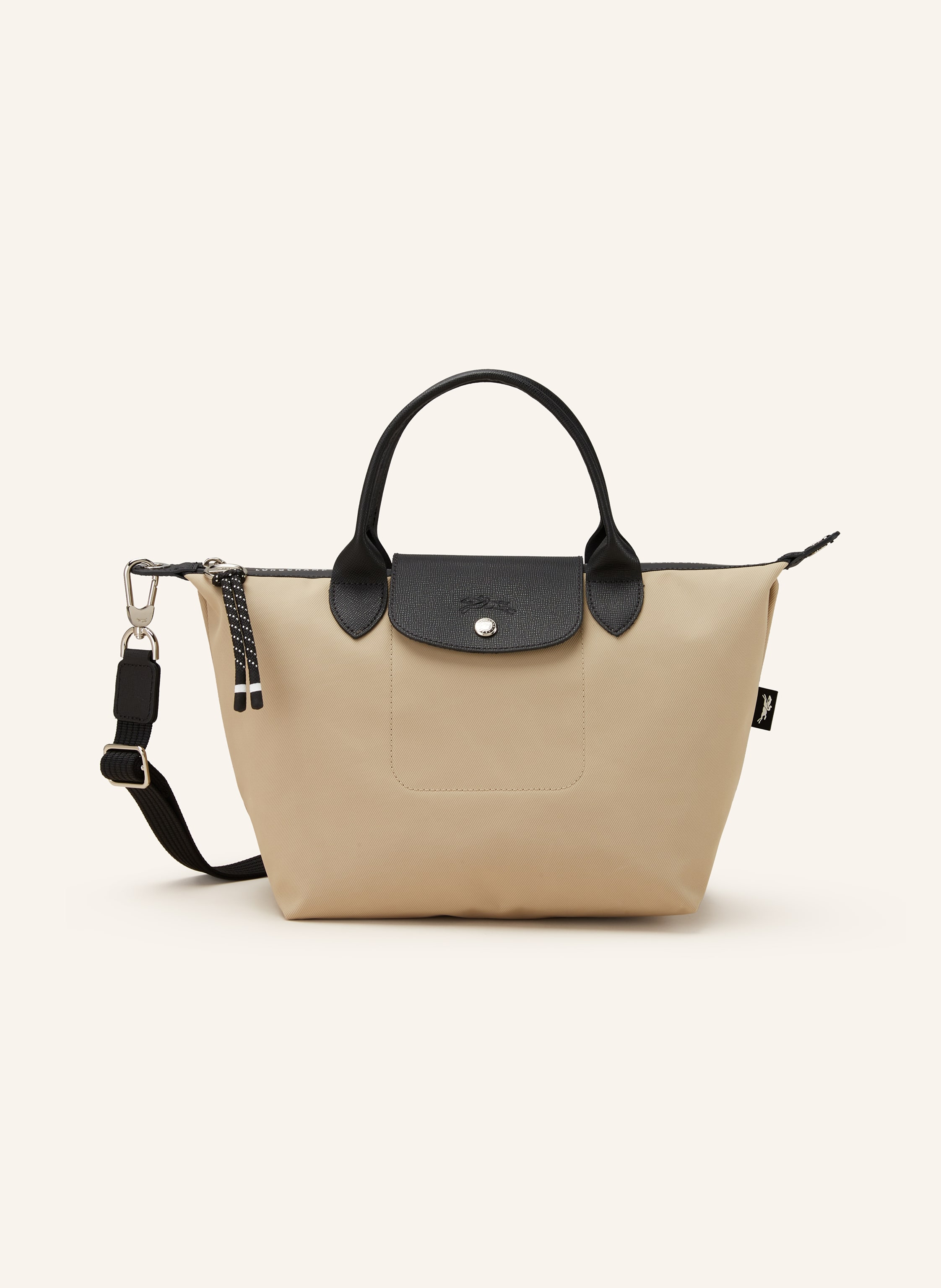 Longchamp Textil mit Lederdetails. Schließt mit Reißverschluss und Druckknopf. Längenverstellbarer Schulterriemen. Innen ein Hauptfach. Steckfach für Smartphone & Co. Label-Wording auf dem Reißverschluss. Logo- Small in creme