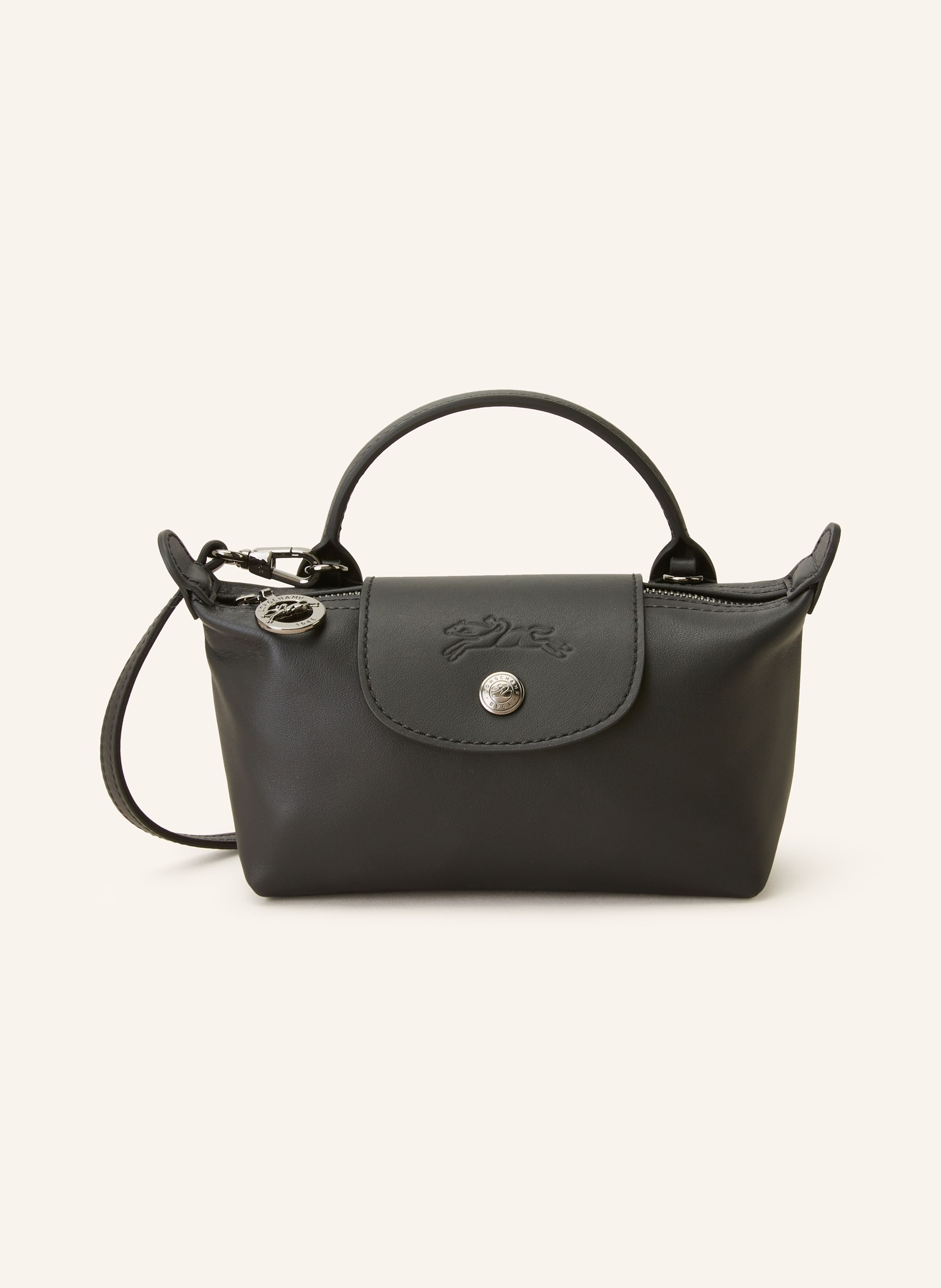 Longchamp Glattleder. Schließt mit Druckknopf und Reißverschluss. Ein Tragehenkel. Abnehmbarer, längenverstellbarer Schulterriemen. Ein Hauptfach innen. Ein kleines Kartensteckfach. Label-Prägung auf der Rückse in schwarz