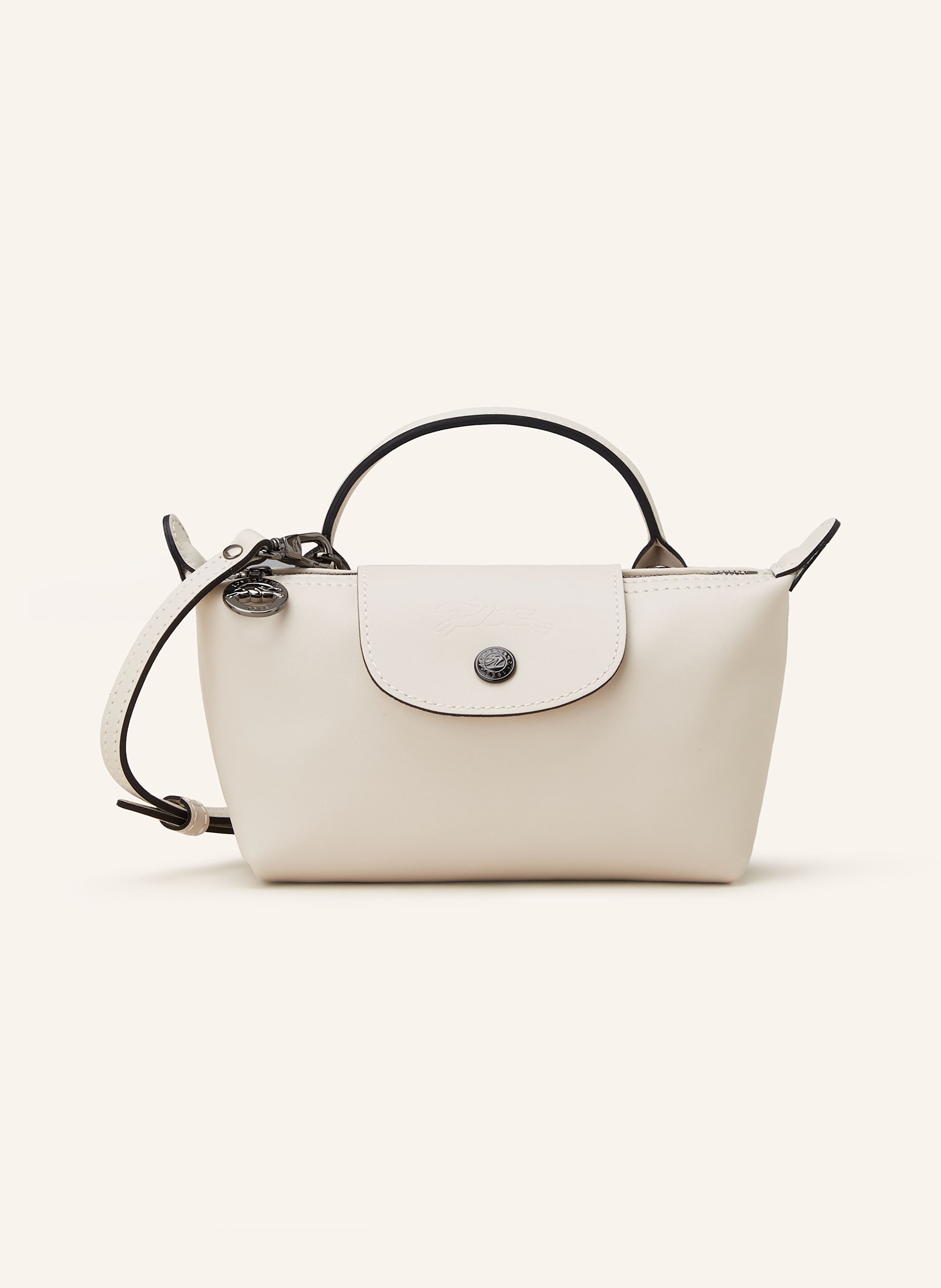 Longchamp Glattleder. Schließt mit Druckknopf und Reißverschluss. Ein Tragehenkel. Abnehmbarer, längenverstellbarer Schulterriemen. Ein Hauptfach innen. Ein kleines Kartensteckfach. Label-Prägung auf der Rückse in creme