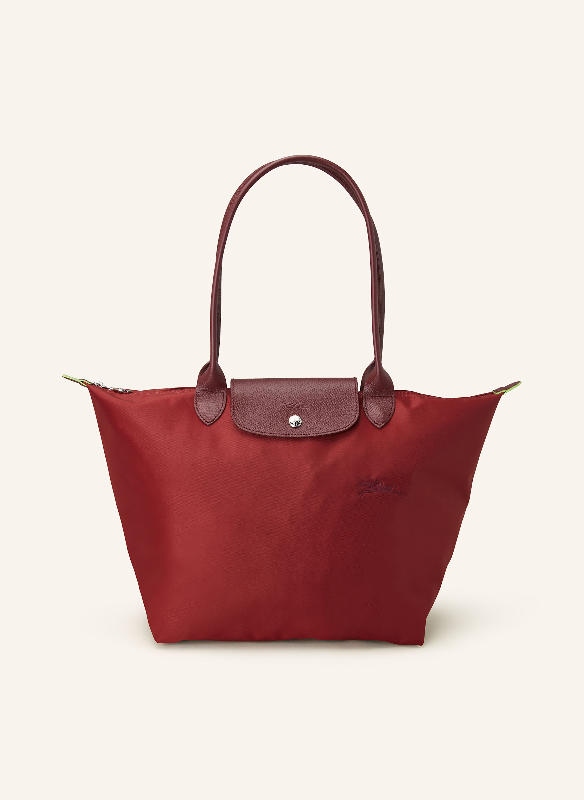 Longchamp Textil mit Lederdetails. Reptilienoptik. Silberfarbene Metalldetails. Schließt mit einem Reißverschluss. Zwei Trageriemen. Überschlag mit Druckknopf zum Falten. Innen ein Hauptfach. Ein Steckfach für in dunkelrot