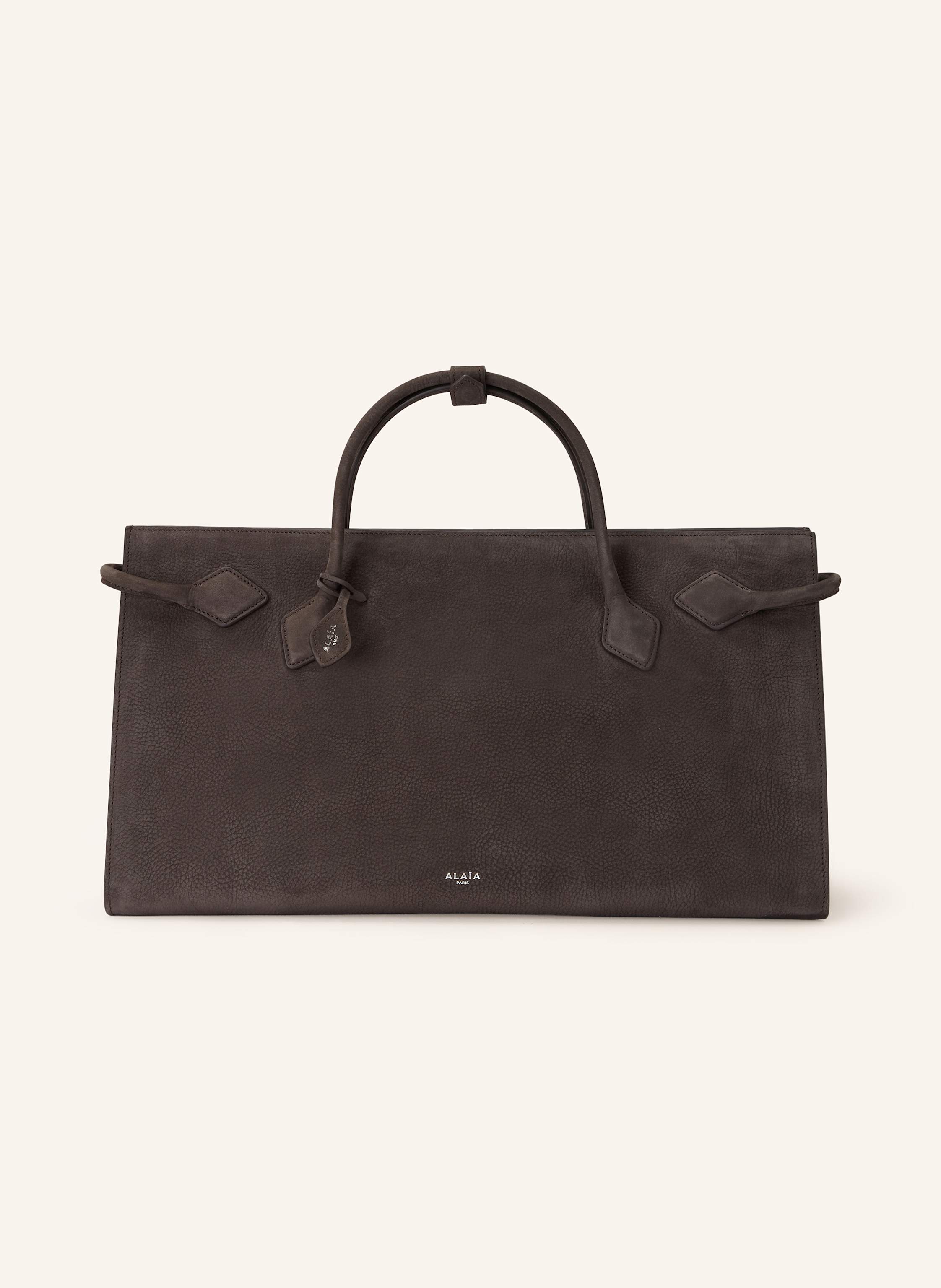 Alaïa Genarbtes Nubukleder. Zwei Tragegriffe. Seitliche Riemen. Innen ein Hauptfach. Ein Steckfach für Smartphone & Co. Verstärkter Taschenboden. Label-Emblem auf der Front. Made in Italy in dunkelgrau