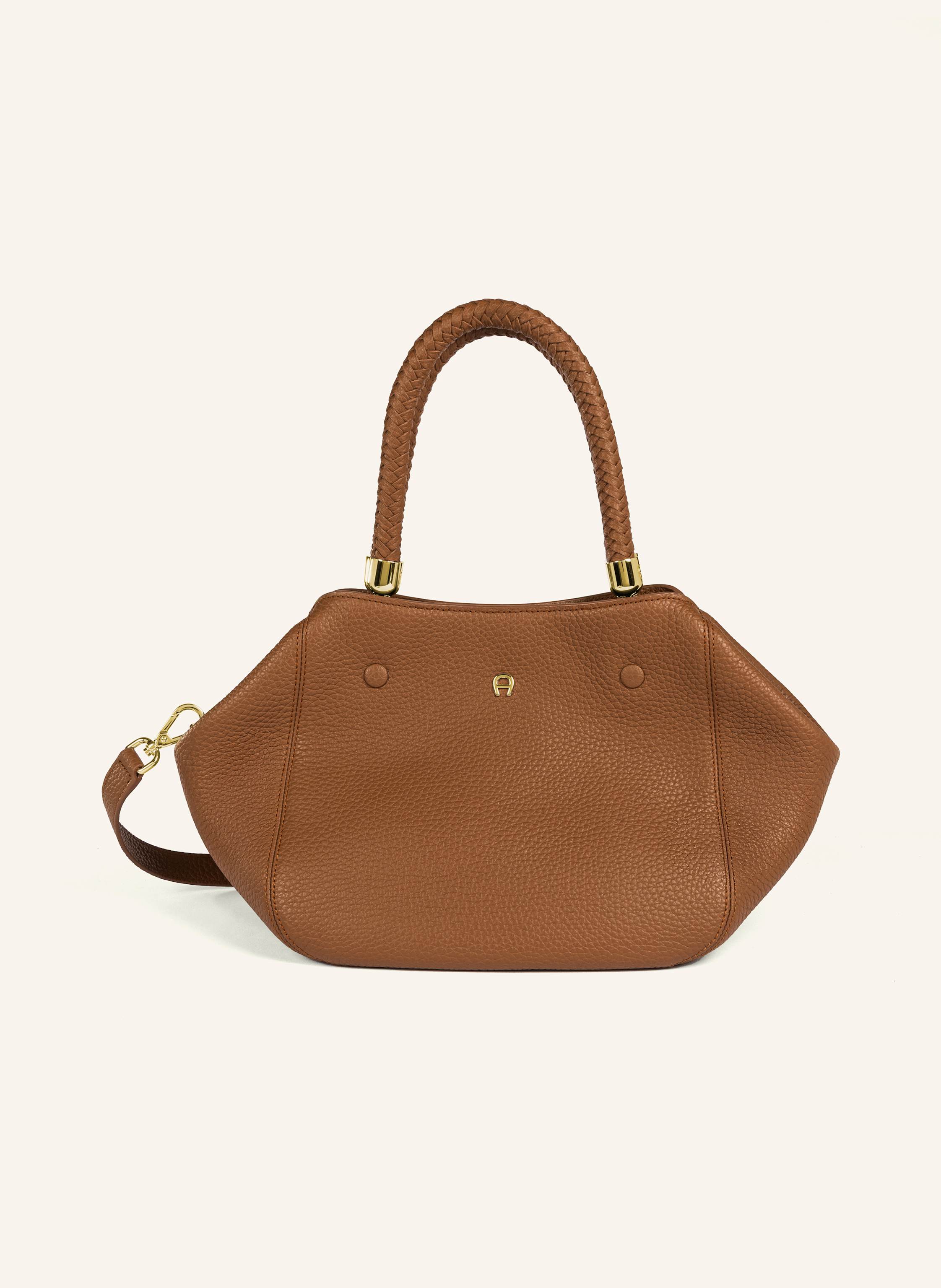 Aigner Die Carré Soft M ist die perfekte kleine Begleiterin für jeden Tag. Ob beim Stadtbummel oder unterwegs ins Büro – ihr weiches Design und der elegante AIGNER Look machen sie zu einem zuverlässigen Lieb in cognac
