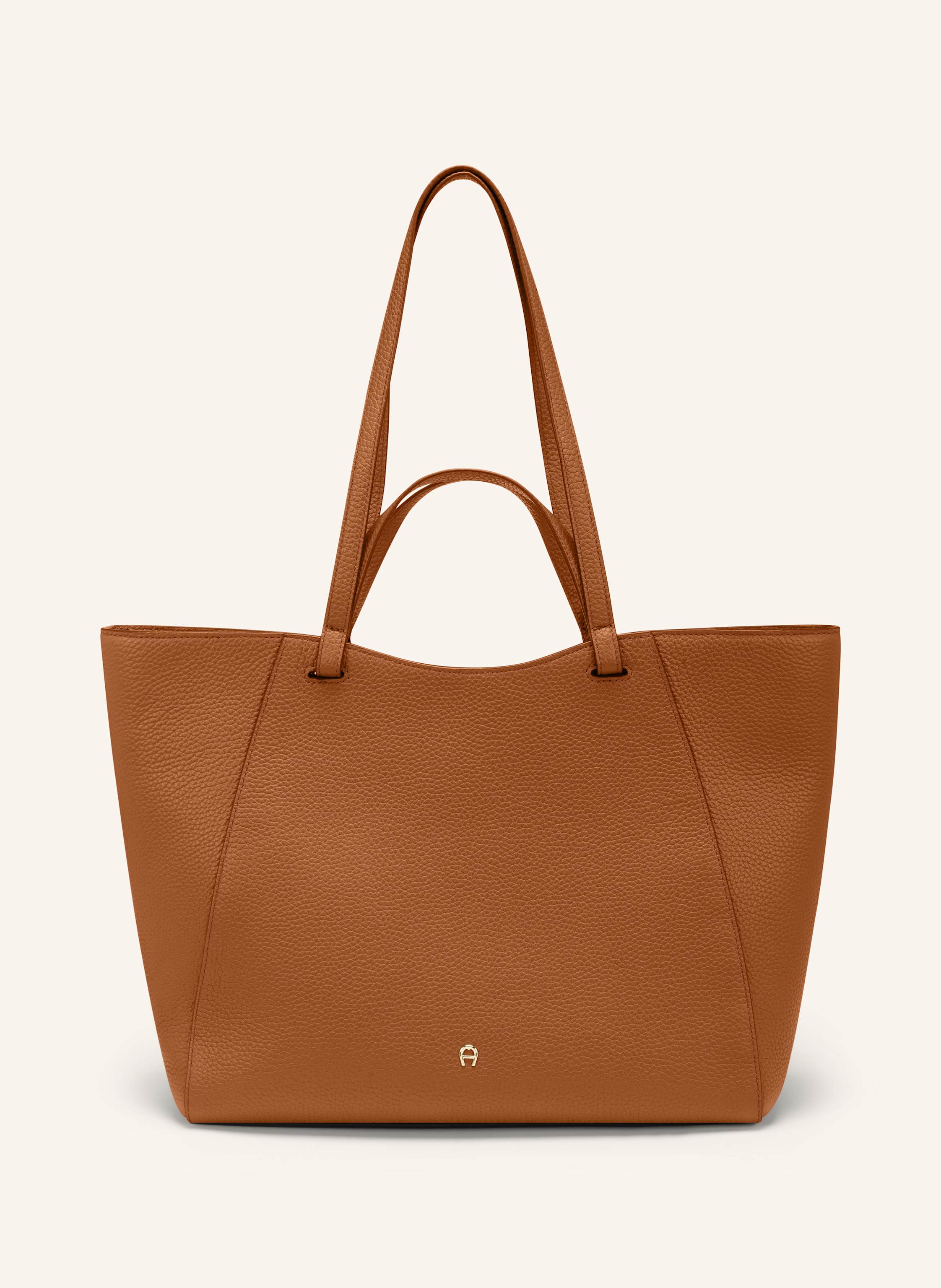 Aigner Diese Pura Variante bietet eine besonders harmonische Silhouette mit dezenter Ausstrahlung. Ein Modell, das Eleganz und Alltagstauglichkeit perfekt verbindet und verlässlich an Ihrer Seite bleibt – Ta in cognac
