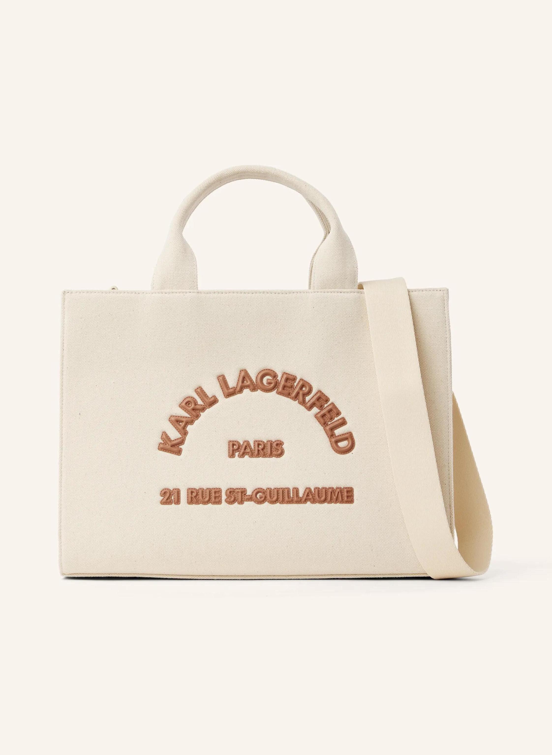 Karl Lagerfeld A structured tote with a spacious square silhouette that moves effortlessly from work to weekend. Twin handles and a detachable strap offer versatile, tactile comfort. Spacious and structured, square- in beige