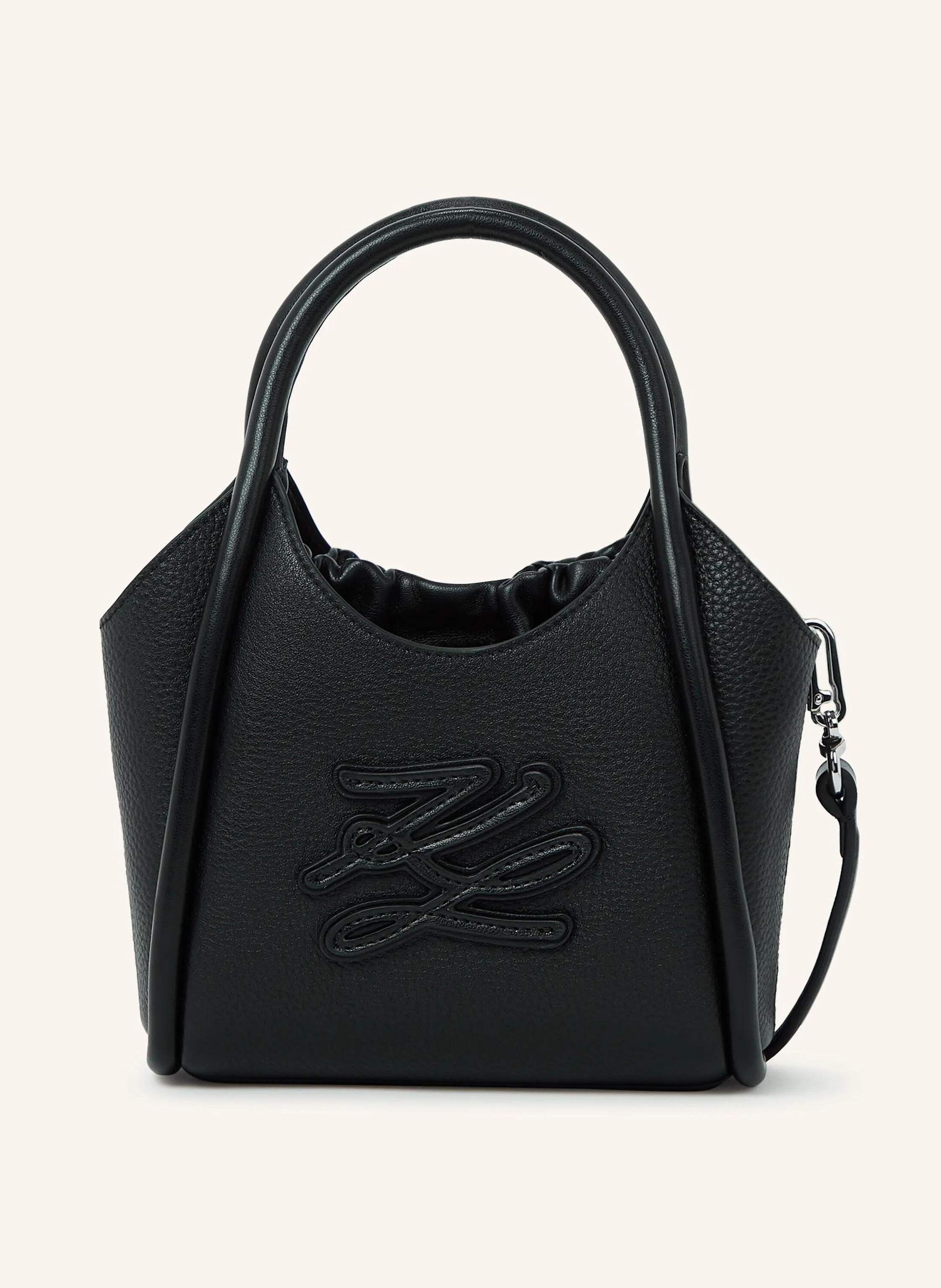 Karl Lagerfeld The K/Autograph mini tote bag blends elegant design with practical versatility. Its supple cow leather and tonal logo create a refined look, while the interior drawstring pouch and adjustable strap ke in schwarz